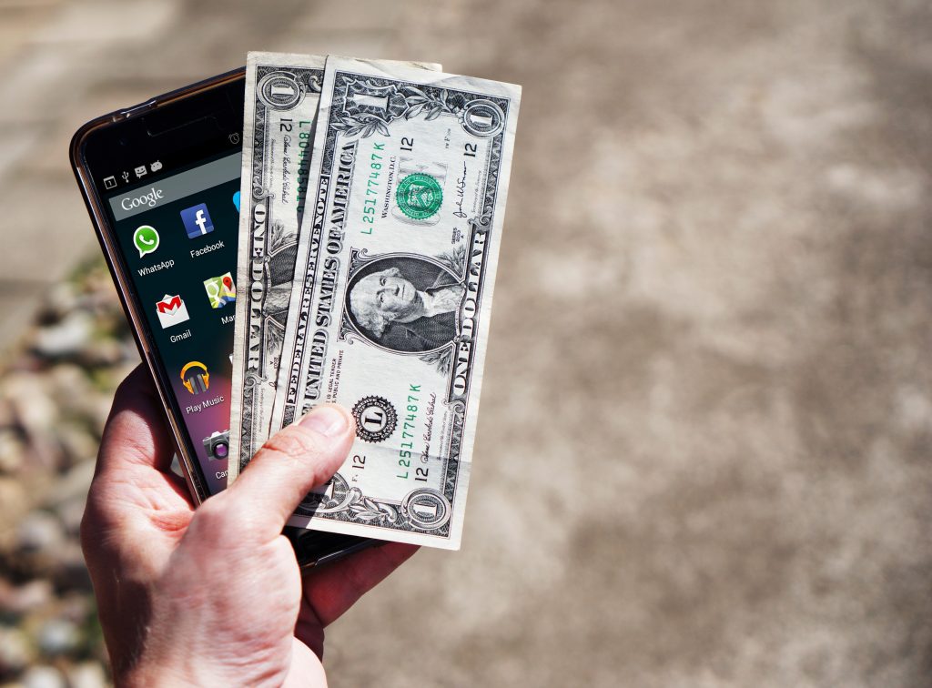 An image of a mobile phone and some cash.